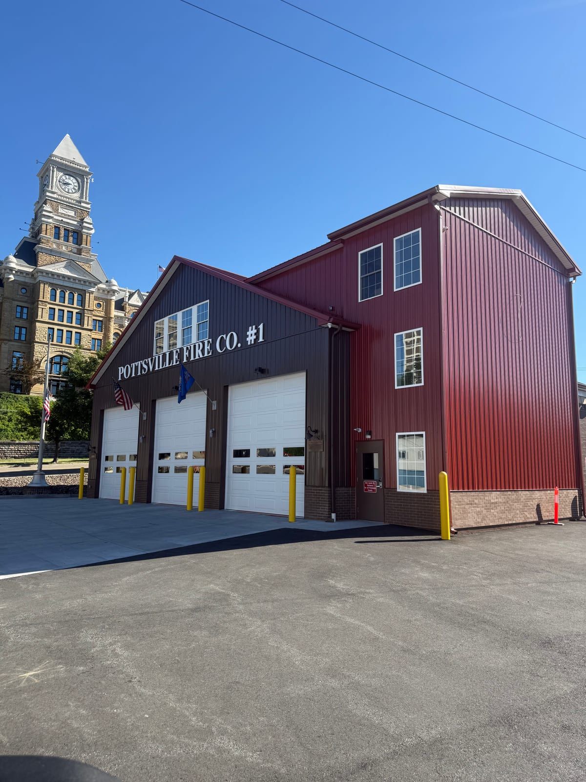 The Pottsville Fire Co. No. 1 firehouse, its facade lettered 'Pottsville Fire Co. #1,' with the Schuylkill County Courthouse tower rising behind it.
