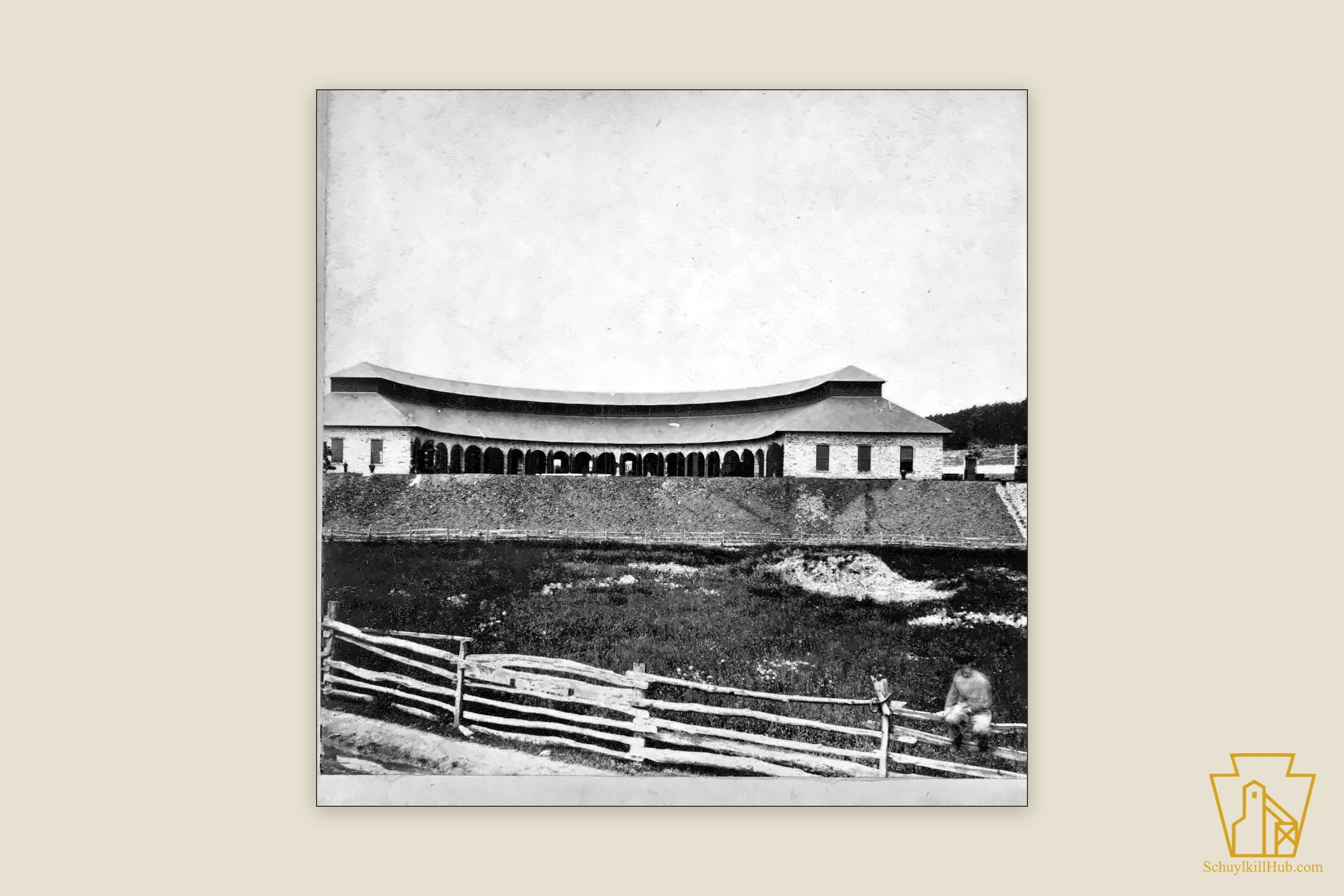 The long arcaded stone engine house beside the Mine Hill Railroad tracks at Cressona — a stereograph frame.