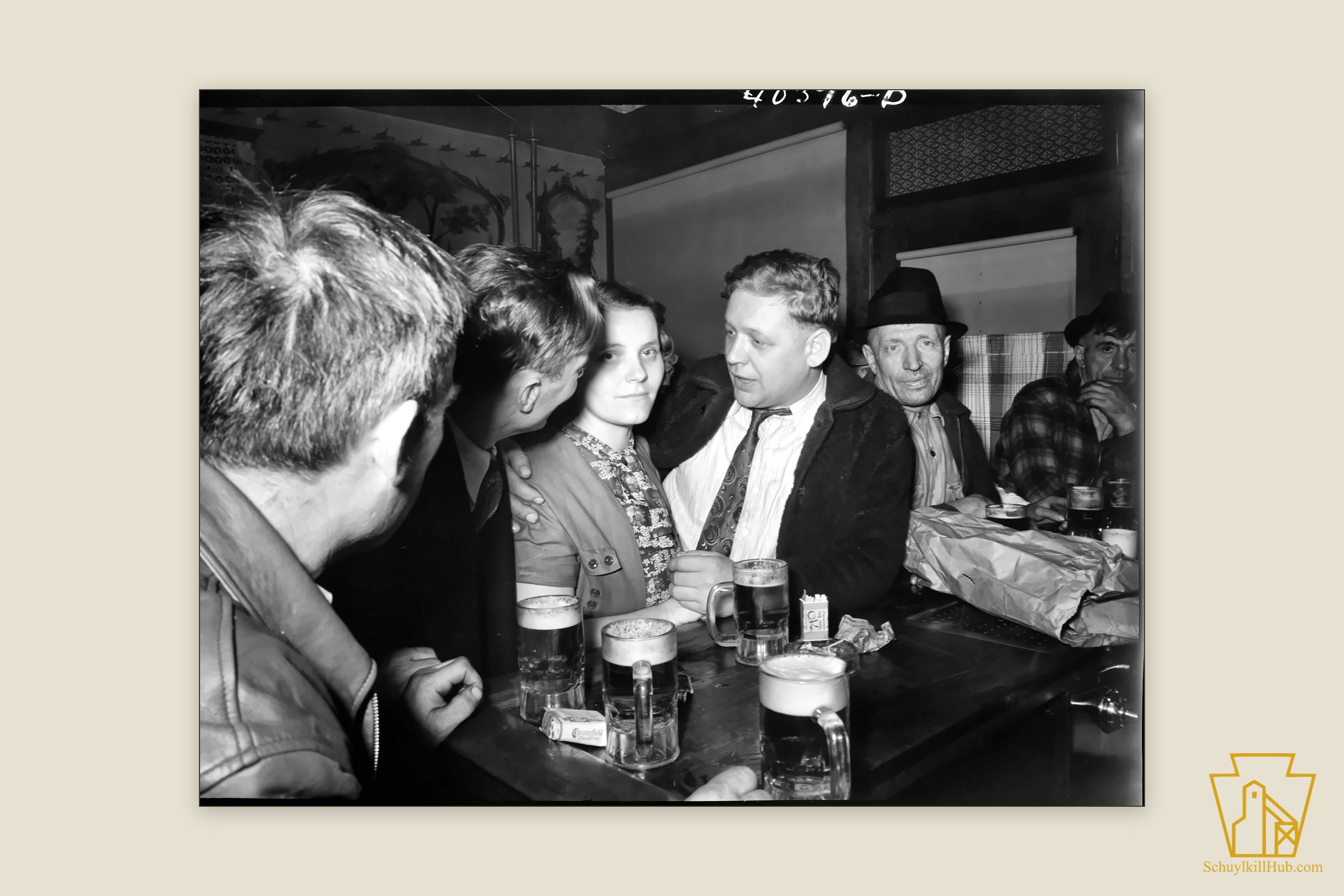 Men and a young woman leaning at Filipek’s bar in Shenandoah, beer mugs and cigarettes on the rail.
