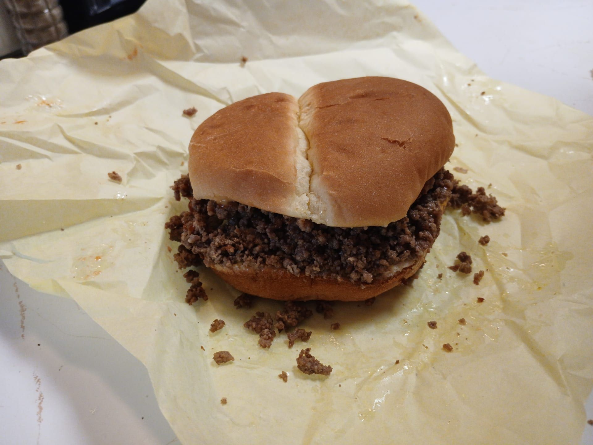 A Coal Region barbecue on a soft white roll, the loose seasoned ground beef spilling onto its wax-paper wrapper.