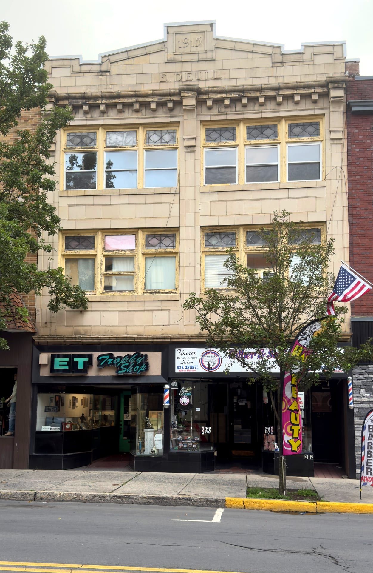 The 1915 E. Deull Building at 202–204 North Centre Street, its terra-cotta parapet carved 'E. Deull' and the date 1915, above upper-floor windows with leaded-glass transoms and a row of ground-floor storefronts.