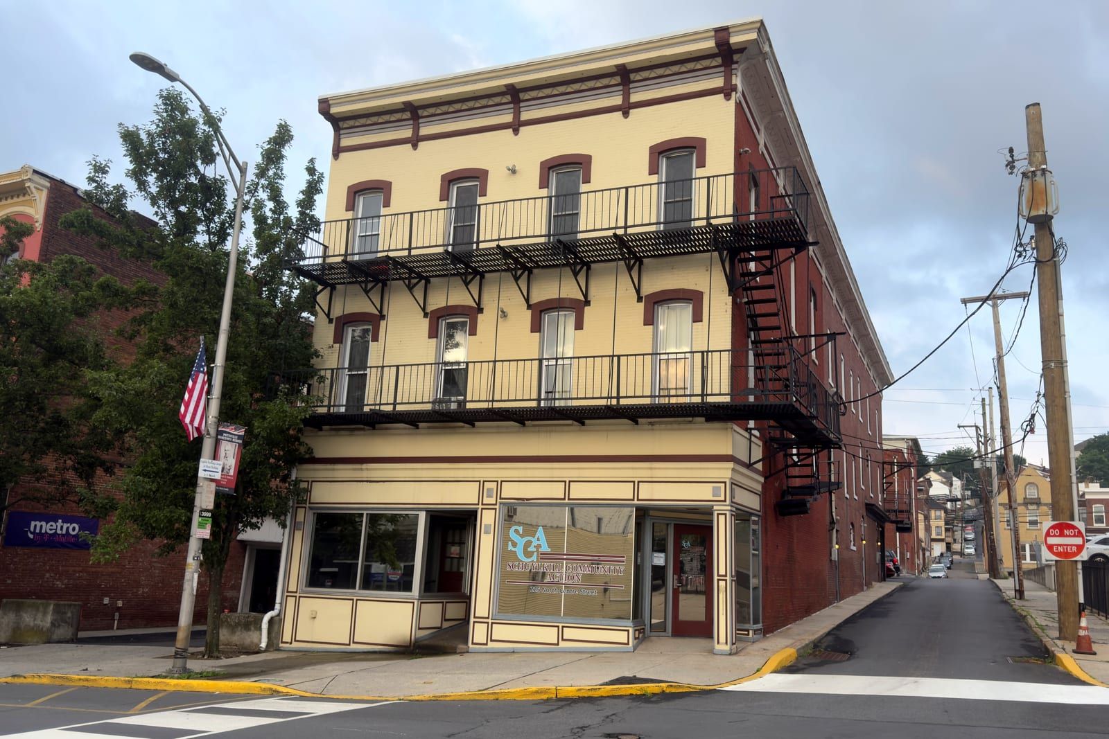 225 North Centre Street on the corner of Centre and Race Streets, its long side elevation and fire escape stepping downhill along Race Street beside the Schuylkill Community Action storefront.