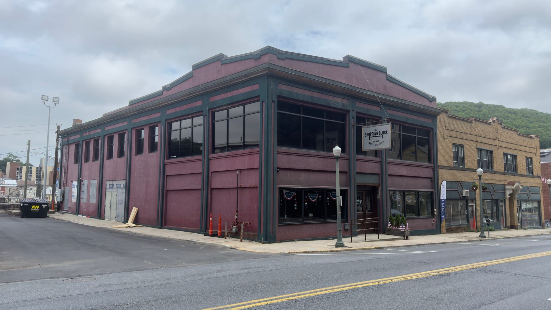 370 South Centre Street, Pottsville — a two-story masonry commercial building painted deep maroon with dark green trim on its pilasters and window frames, a canted corner entrance under a hanging 'Chopping Block' sign, wide storefront windows with patriotic bunting, and a wooded ridge behind.