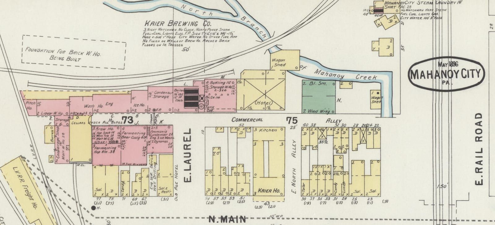 A hand-colored 1896 fire-insurance map of the Kaier Brewing Co. complex in Mahanoy City: a long row of pink brick buildings — wash house, ice house, condenser storage, boilers, bottling and storage warehouse, brew house with hop sack, mash tub, and malt mill floors — between North Main Street and the North Branch of Mahanoy Creek, with a dashed outline noting 'Foundation for brick w. ho. being built' and the May 1896 Mahanoy City title cartouche at right.