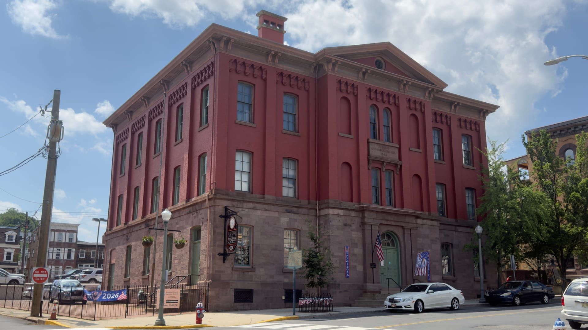 The Schuylkill County Historical Society, in the former Centre Street Grammar School, seen from the corner of North Centre and Race streets: a three-story red-brick building on a rusticated sandstone base, with arched upper windows, a corbeled cornice, a pedimented center bay, and a rooftop cupola.