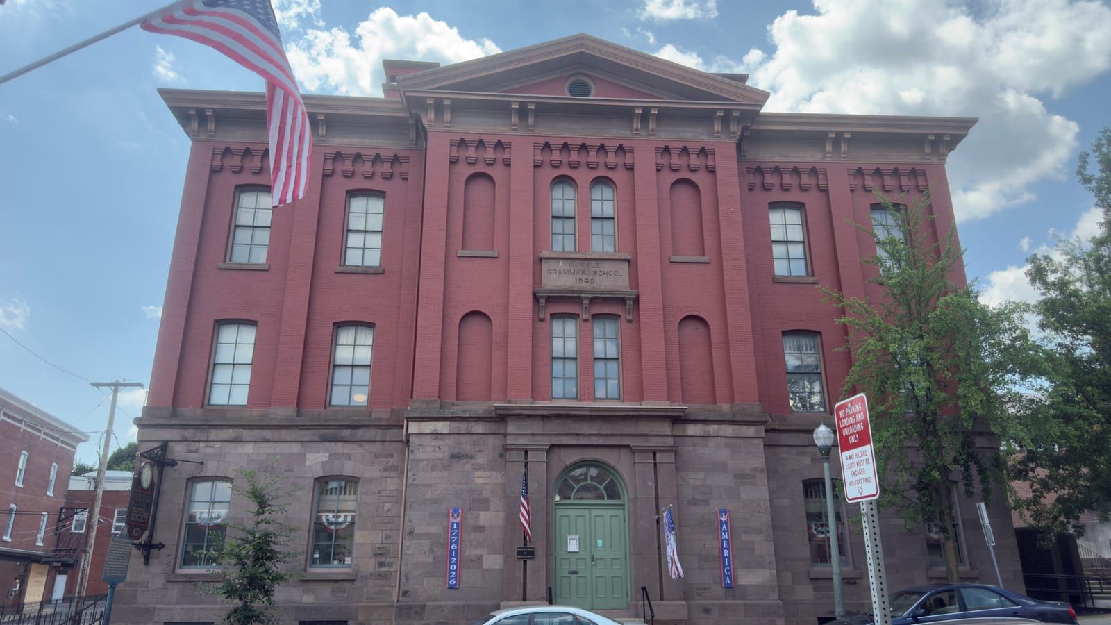 The North Centre Street front of the Schuylkill County Historical Society — a green arched doorway flanked by banners, below three stories of red brick above a rusticated sandstone ground floor.