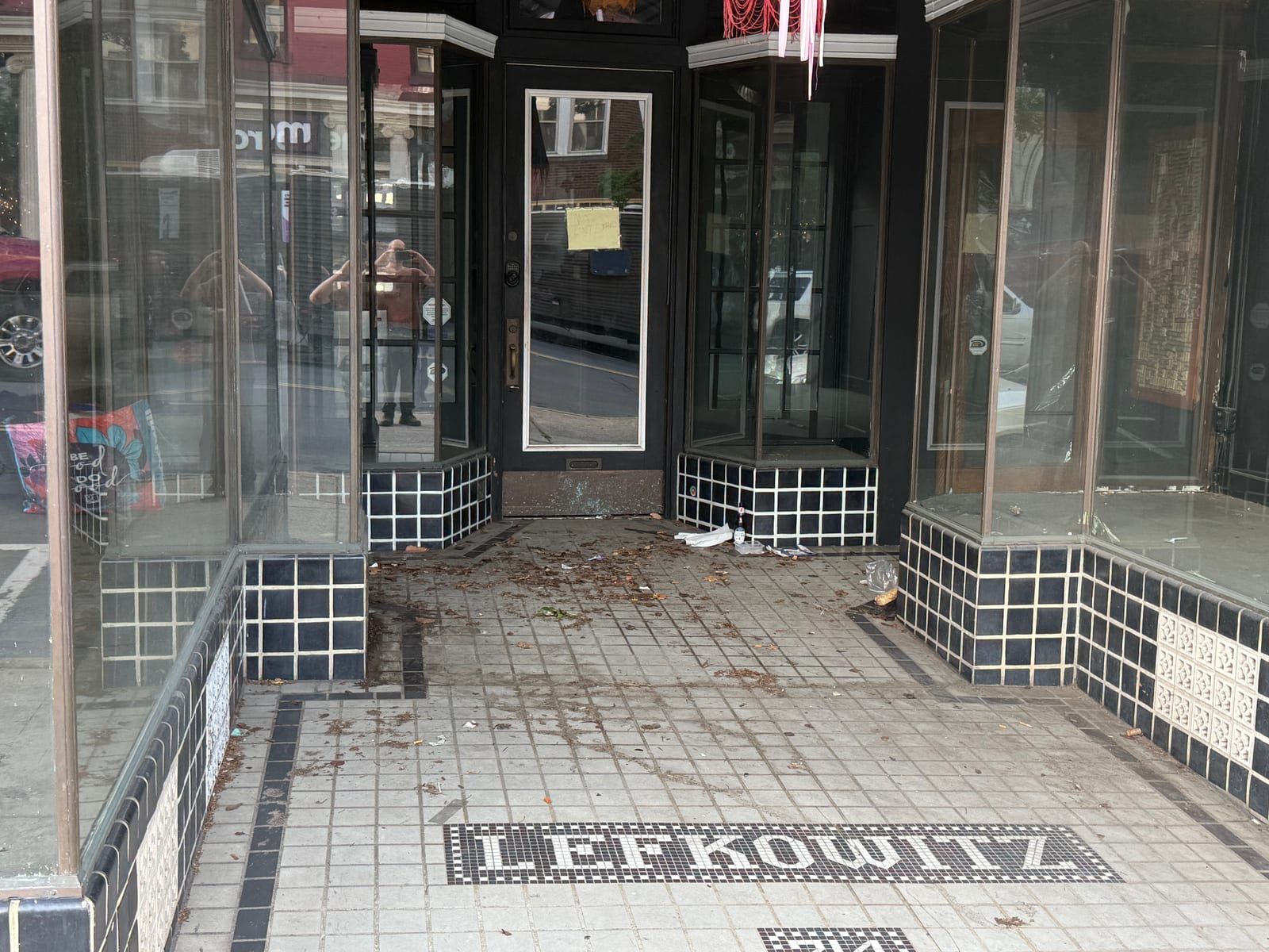 The recessed entrance of 214 North Centre Street: display windows angled inward over black-and-white checkered tile bulkheads, and the name LEFKOWITZ set in mosaic tile in the floor.