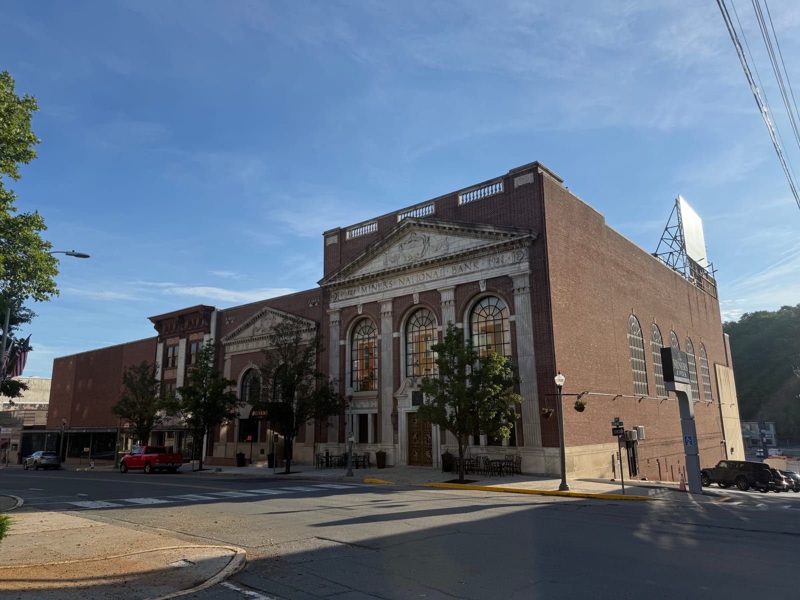 The former Miners National Bank seen from the street corner — the pedimented marble-and-brick front on South Centre Street and the building's long brick flank running back along South Progress Avenue.