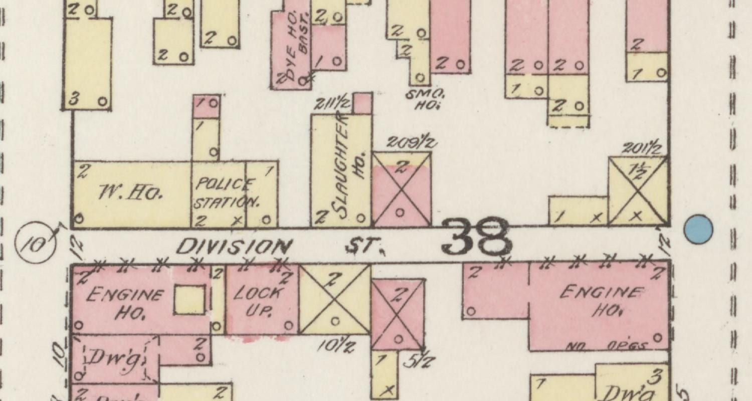 A hand-colored Sanborn insurance-map detail of block 38, Division Street running through it, with two buildings marked ENGINE HO. and one marked LOCK UP on the south side of the lane and a frame building marked POLICE STATION across the way.