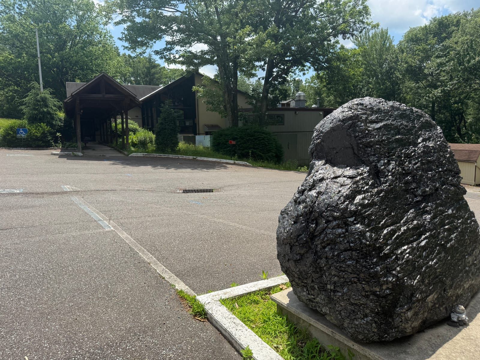 The former Pottsville Club on Sharp Mountain — a low 1960s lodge building behind a parking lot, with a polished anthracite-coal boulder in the foreground.