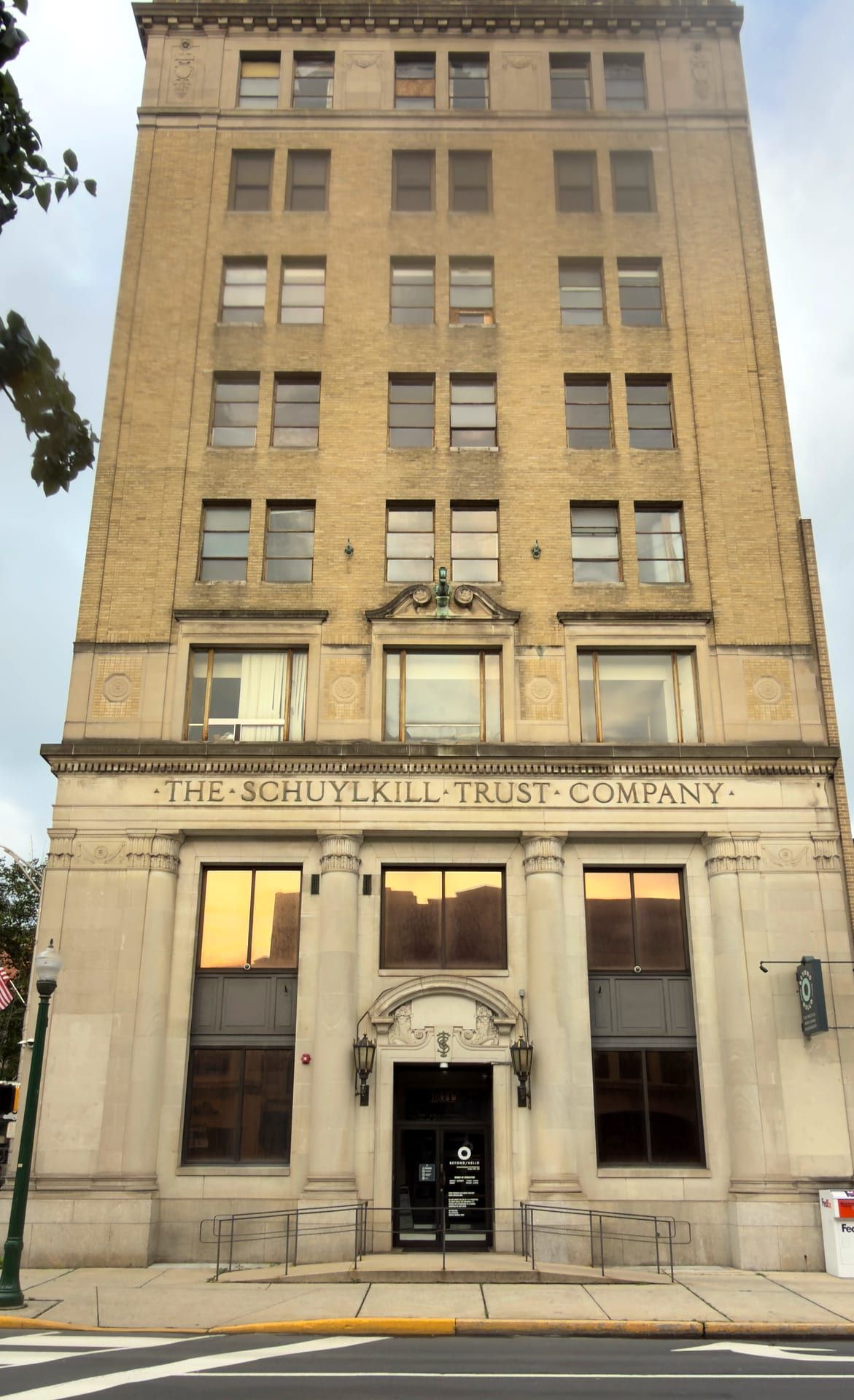The eight-story buff-brick Schuylkill Trust Company Building seen head-on from Centre Street, its stone base carrying the incised frieze 'The Schuylkill Trust Company' above a columned central entrance.