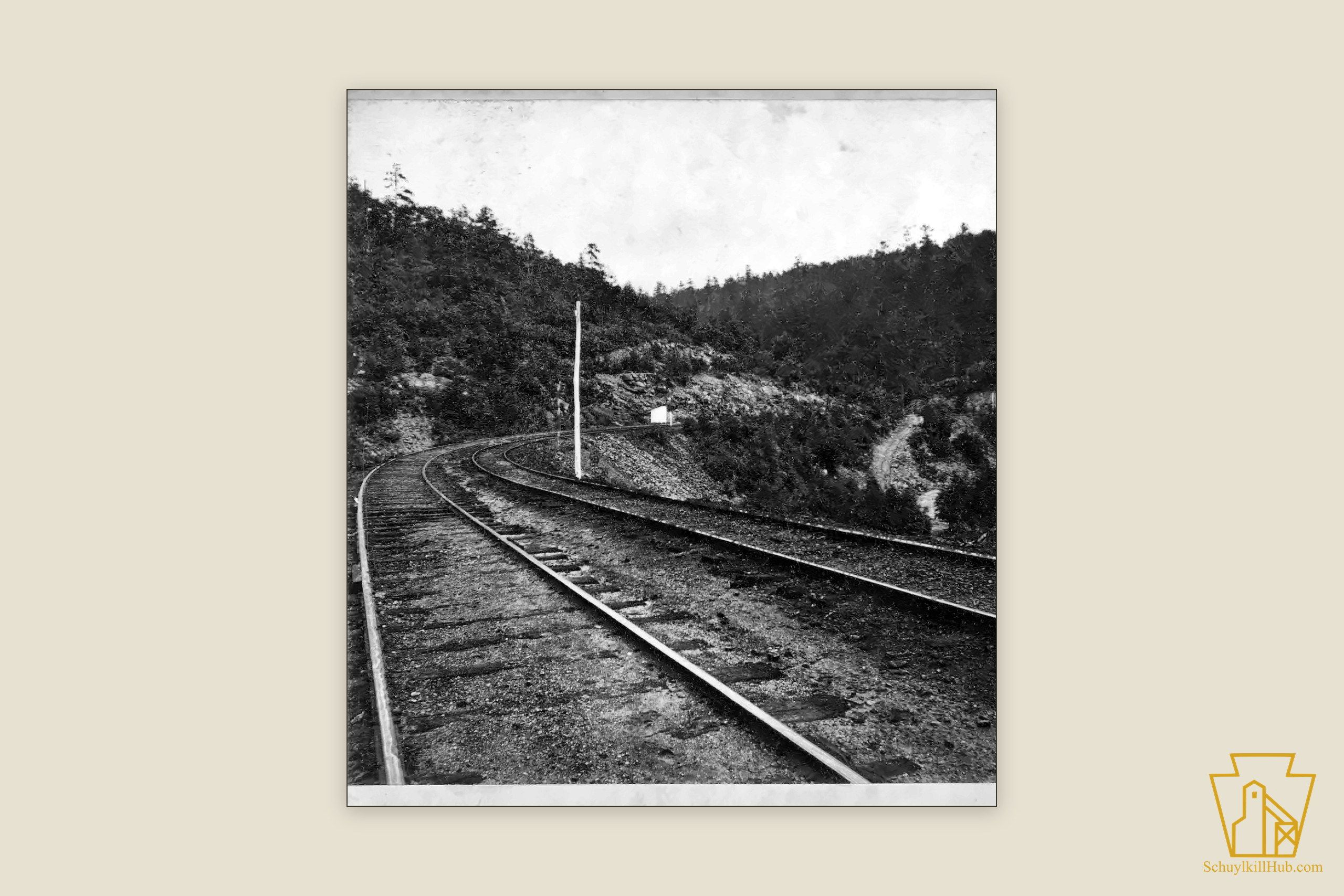 A railroad grade curving through the wooded hills of Schuylkill County — a stereograph frame.