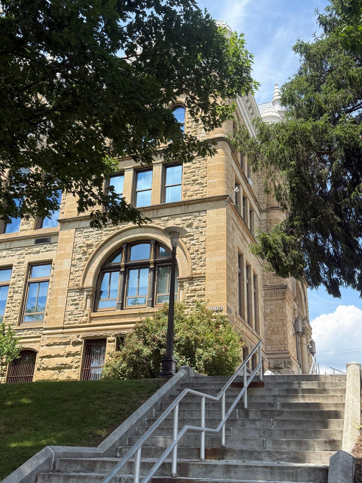 The Schuylkill County Courthouse in Pottsville — a buff sandstone building with grouped round-arched windows, framed by trees.