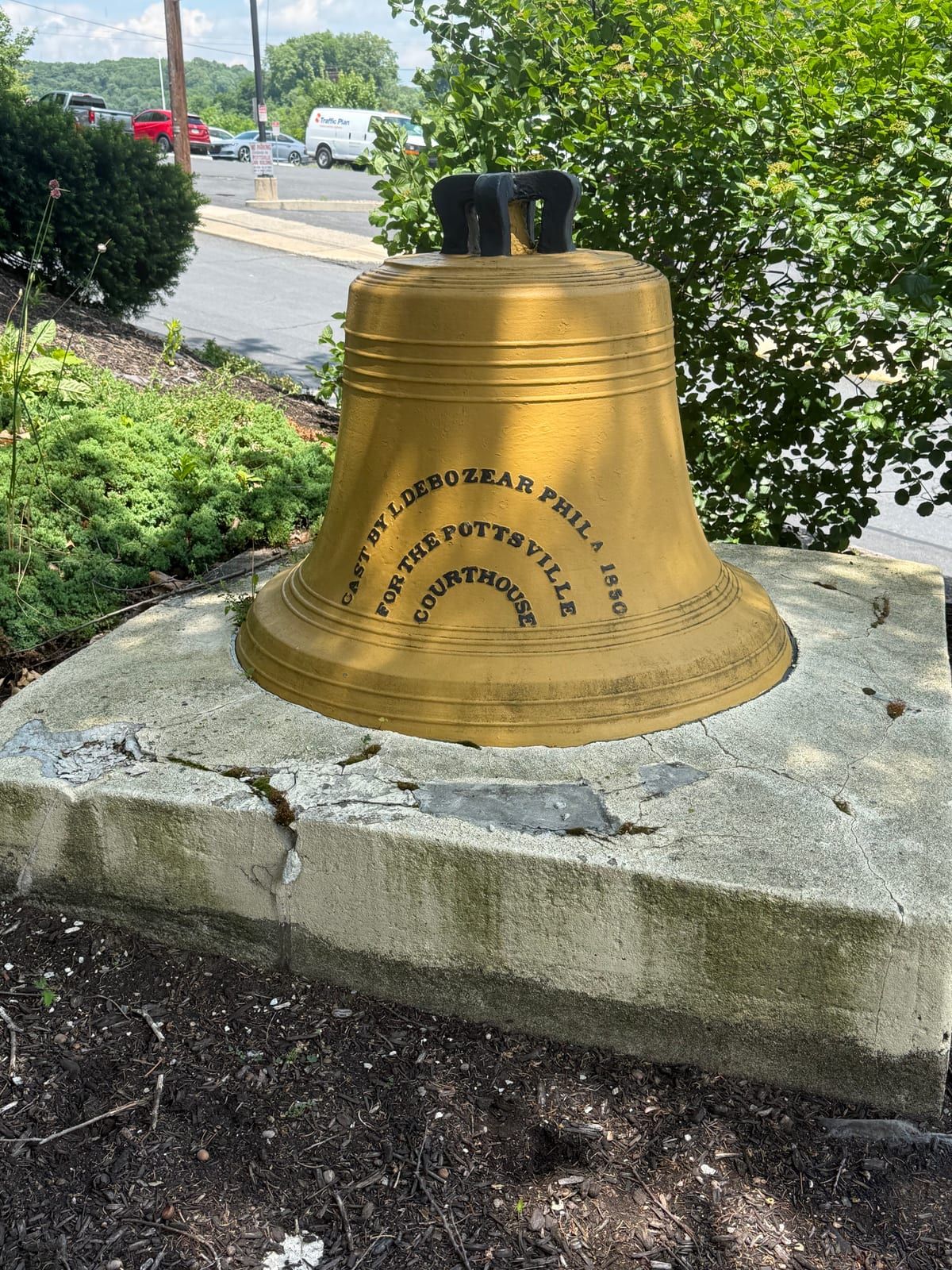 A large brass bell on a stone plinth outside the Schuylkill County Courthouse, its raised inscription reading 'Phila. 1850' and 'for the Pottsville courthouse.'
